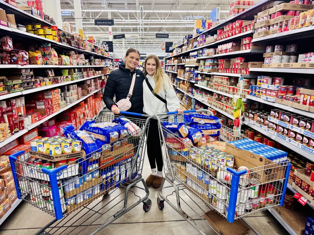Two volunteers shopping for groceries to donate